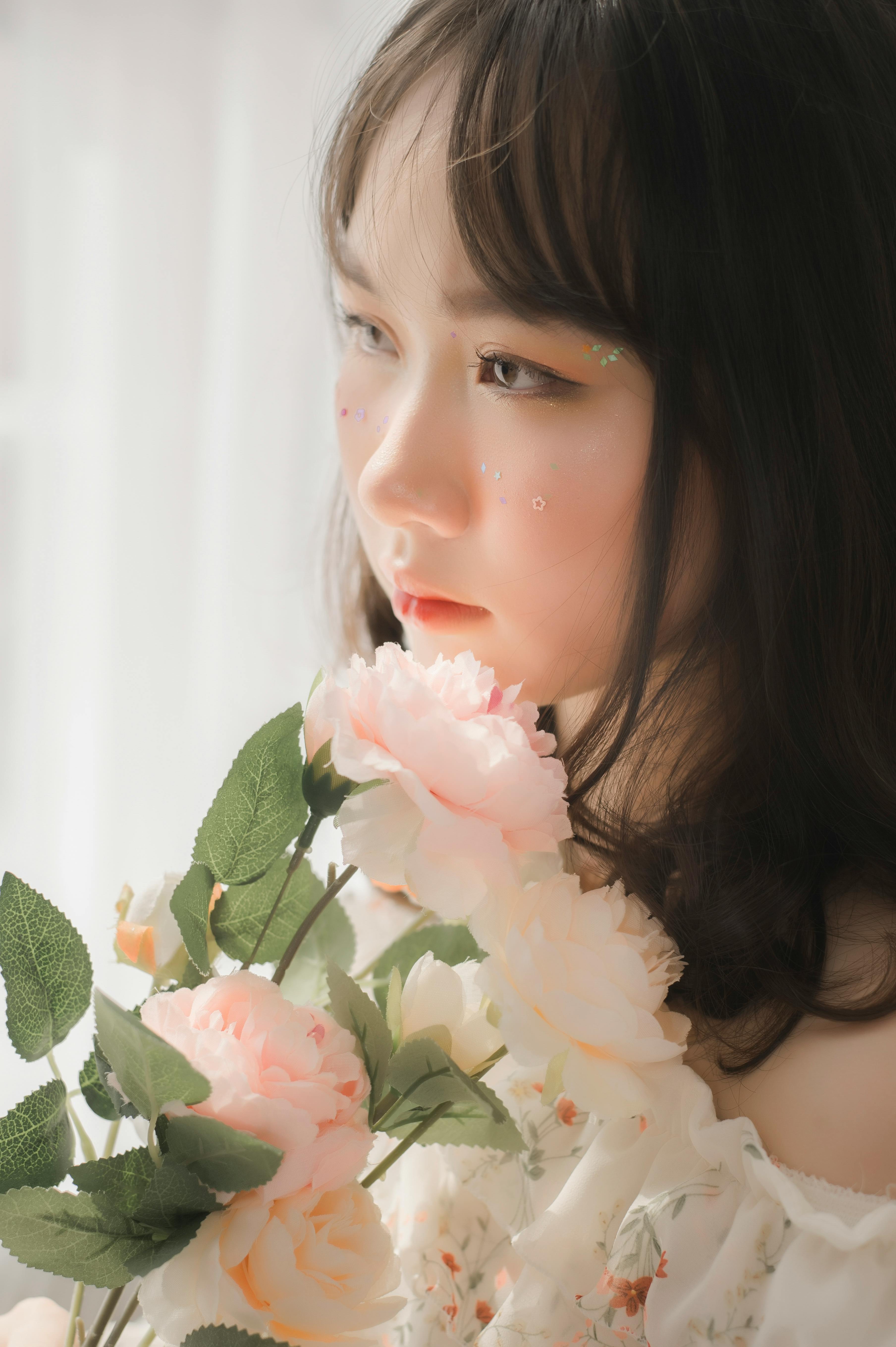 A dreamy portrait of a woman holding soft flowers, captured with warm lighting.