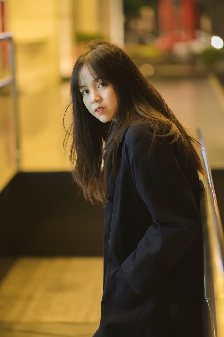 Young Woman In A Black Coat Standing By The Railing 