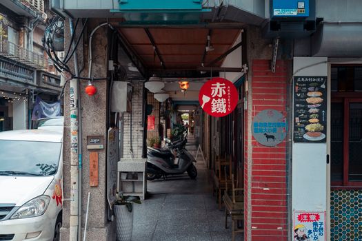 A vibrant urban alley with a parked scooter and local shops, reflecting city life.