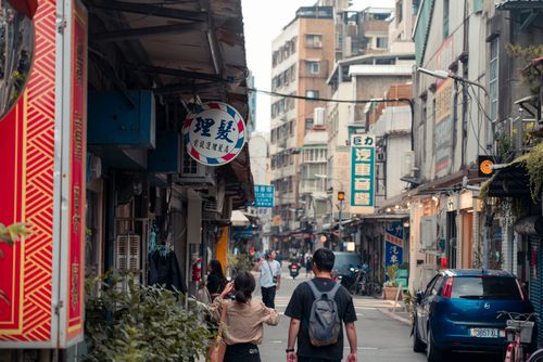 Free Pedestrians walk through a vibrant urban alley with traditional architecture in an Asian city. Stock Photo