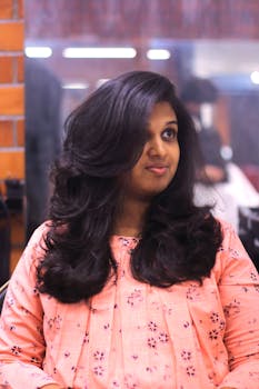 A smiling young woman with long hair in a stylish portrait with a blurred background.