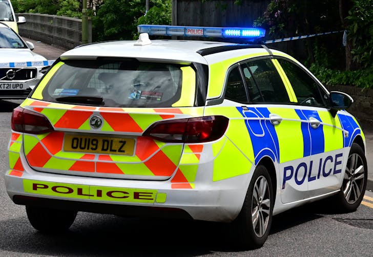 British police car with blue lights on a city road during a roadside stop