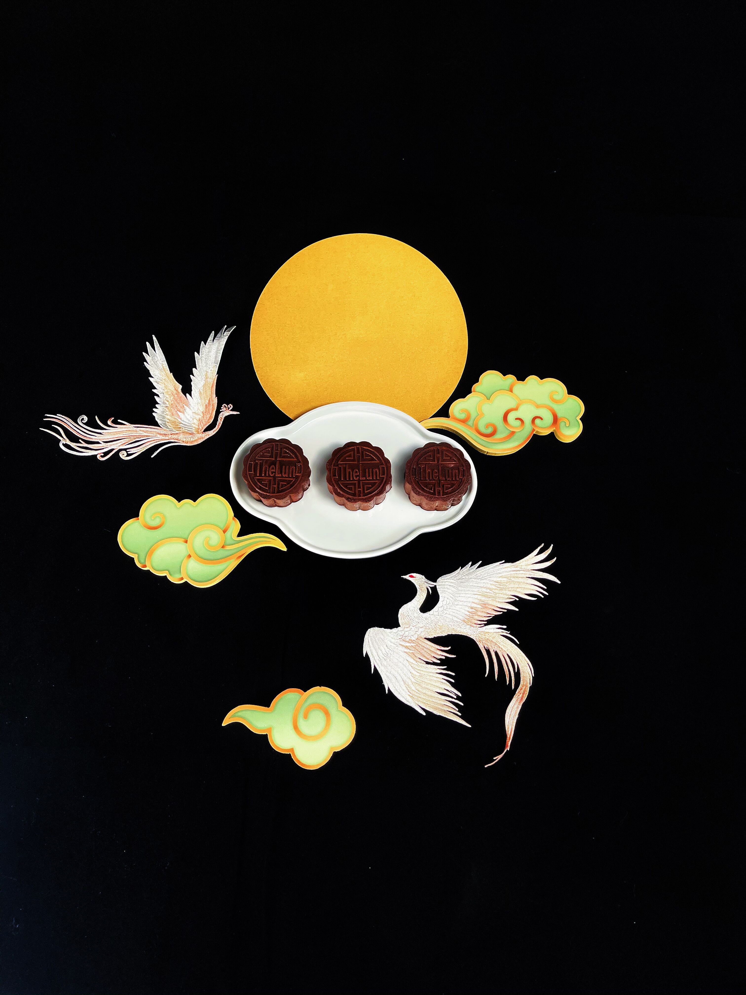 Elegant display of mooncakes with artistic birds and clouds, capturing a traditional festive feel.