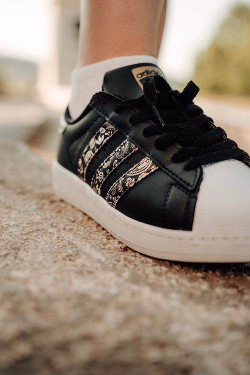 Free Close-up shot of a black and white Adidas sneaker outdoors on a sunny day. Stock Photo
