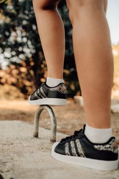 Close-up of stylish black sneakers with athletic stripes outdoors, ideal for fashion and active lifestyle.