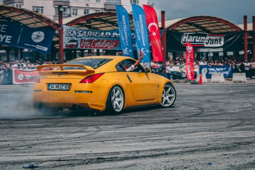 Free A vibrant yellow Nissan sports car performs a thrilling drift at an outdoor event in Türkiye. Stock Photo