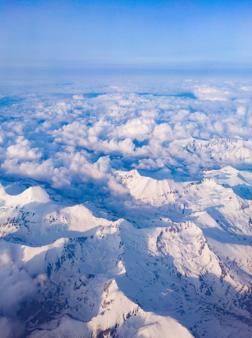 Free Stunning aerial view of snow-covered mountains under a blanket of clouds during winter. Stock Photo