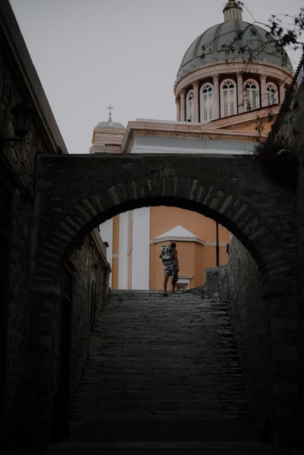 A pedestrian walks under a stone archway towards a historic dome.