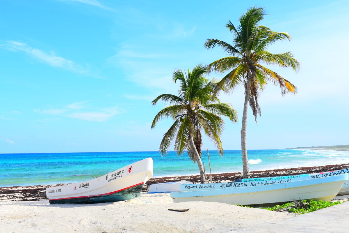 Playa tropical brillante con botes en la orilla bajo cielos azules claros y