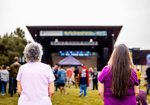 Free View from behind of two women at an outdoor concert enjoying the performance and vibrant atmosphere. Stock Photo