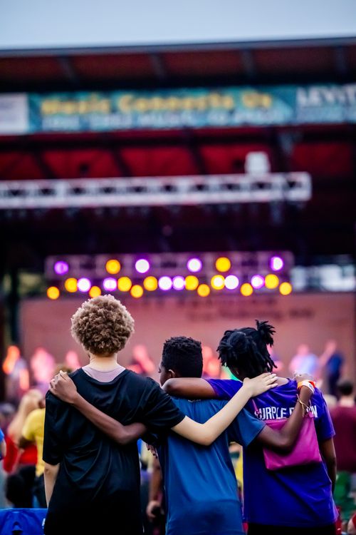 Free A group of teenagers enjoying a concert with colorful stage lights creating a lively atmosphere. Stock Photo