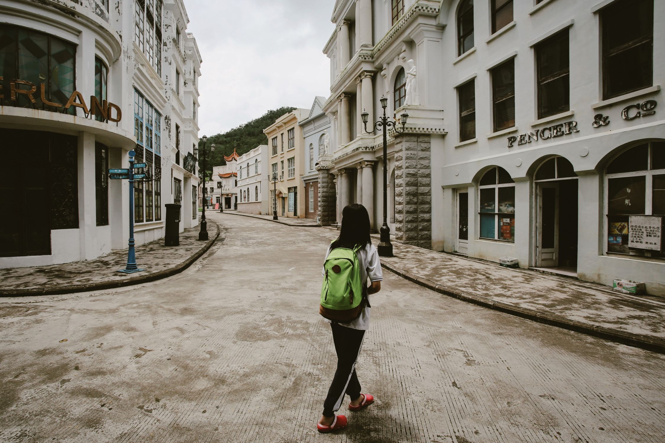 Woman carrying a green daypack on a charming urban street lined with classic architecture