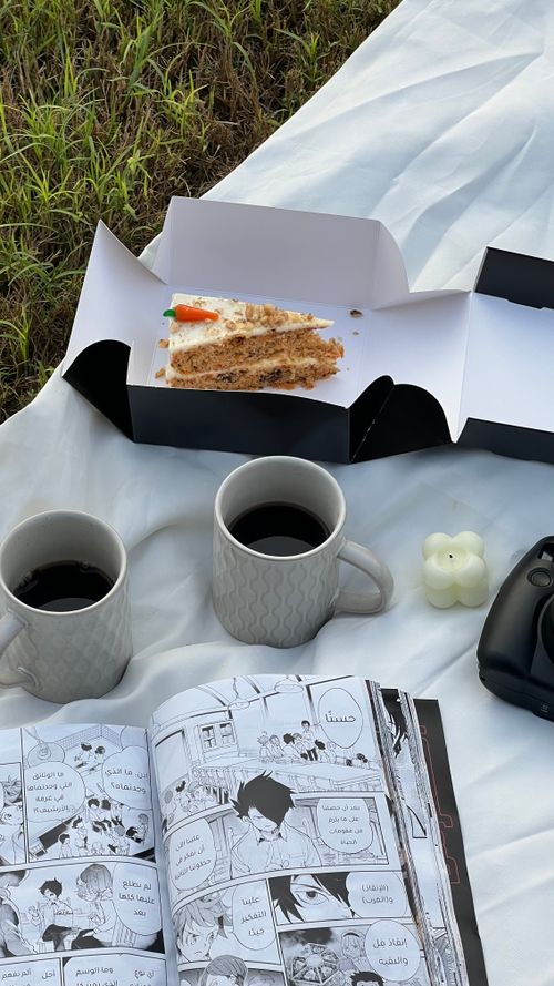 Free Enjoy a peaceful picnic with cake, coffee, and manga amidst nature's embrace. Stock Photo
