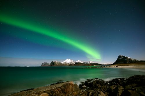 Free Aurora borealis illuminates night sky over coastal landscape in Norway, capturing nature's beauty. Stock Photo