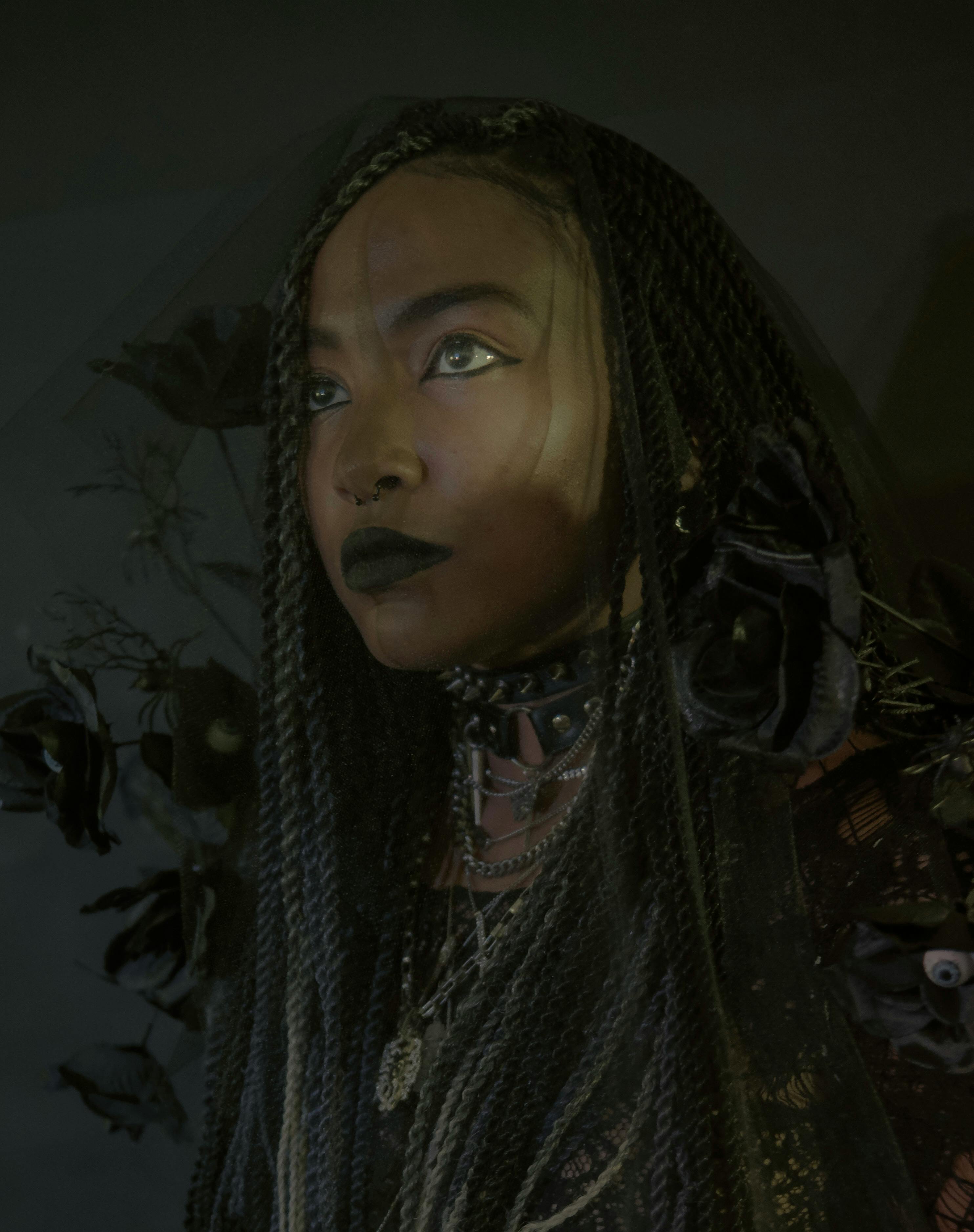 Artistic portrait of a woman with braided hair in dim lighting, exuding a moody and dramatic tone.