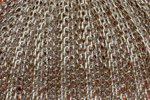 Detailed view of overlapping shiny silver chains creating an intricate metallic texture.