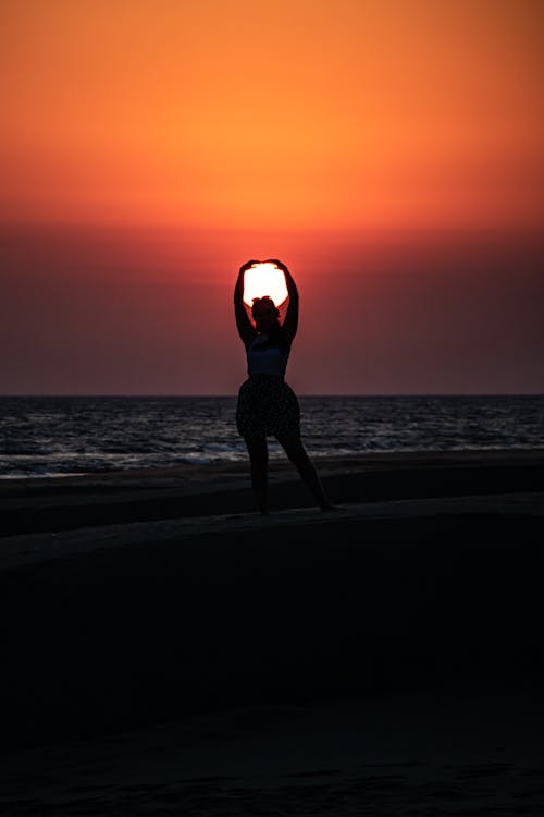A Person Standing on a Beach at Sunset 