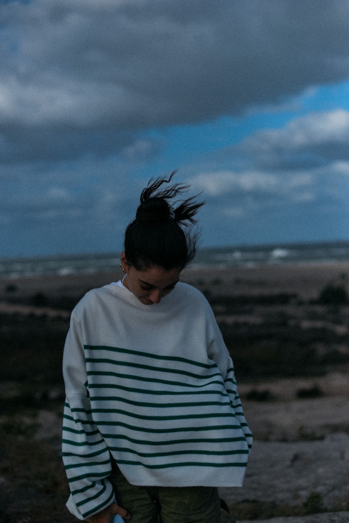 A woman in a loose knit sweater on a windy day by the sea — the easy summer knit