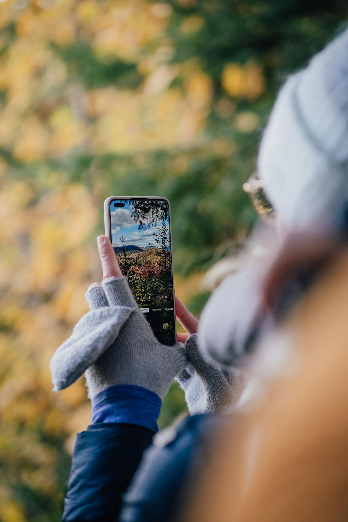 Escursionista con smartphone che fotografa una scena forestale a distanza