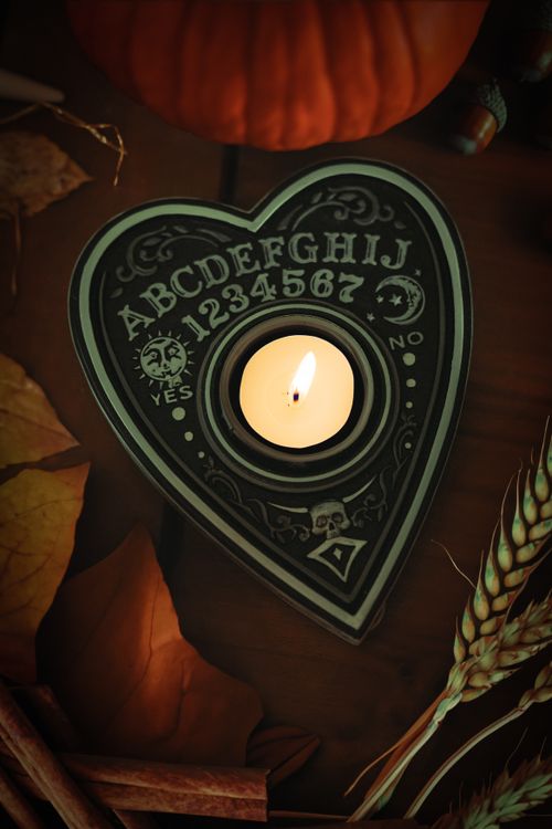 Free Candle in heart-shaped Ouija holder, autumn leaves and decor, Salem ambiance. Stock Photo
