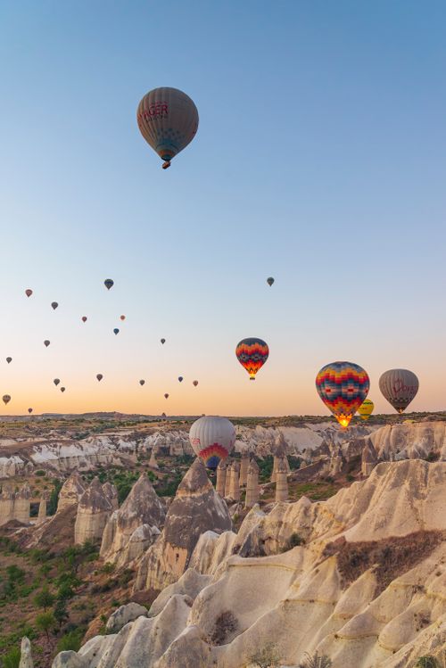 Free Stunning view of hot air balloons soaring over Cappadocia's rock formations at sunset in Türkiye. Stock Photo