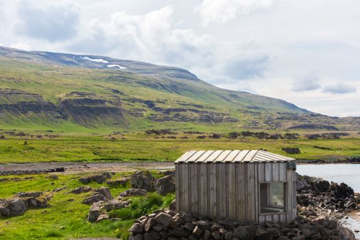 A small wooden cabin sitting on the side of a lake