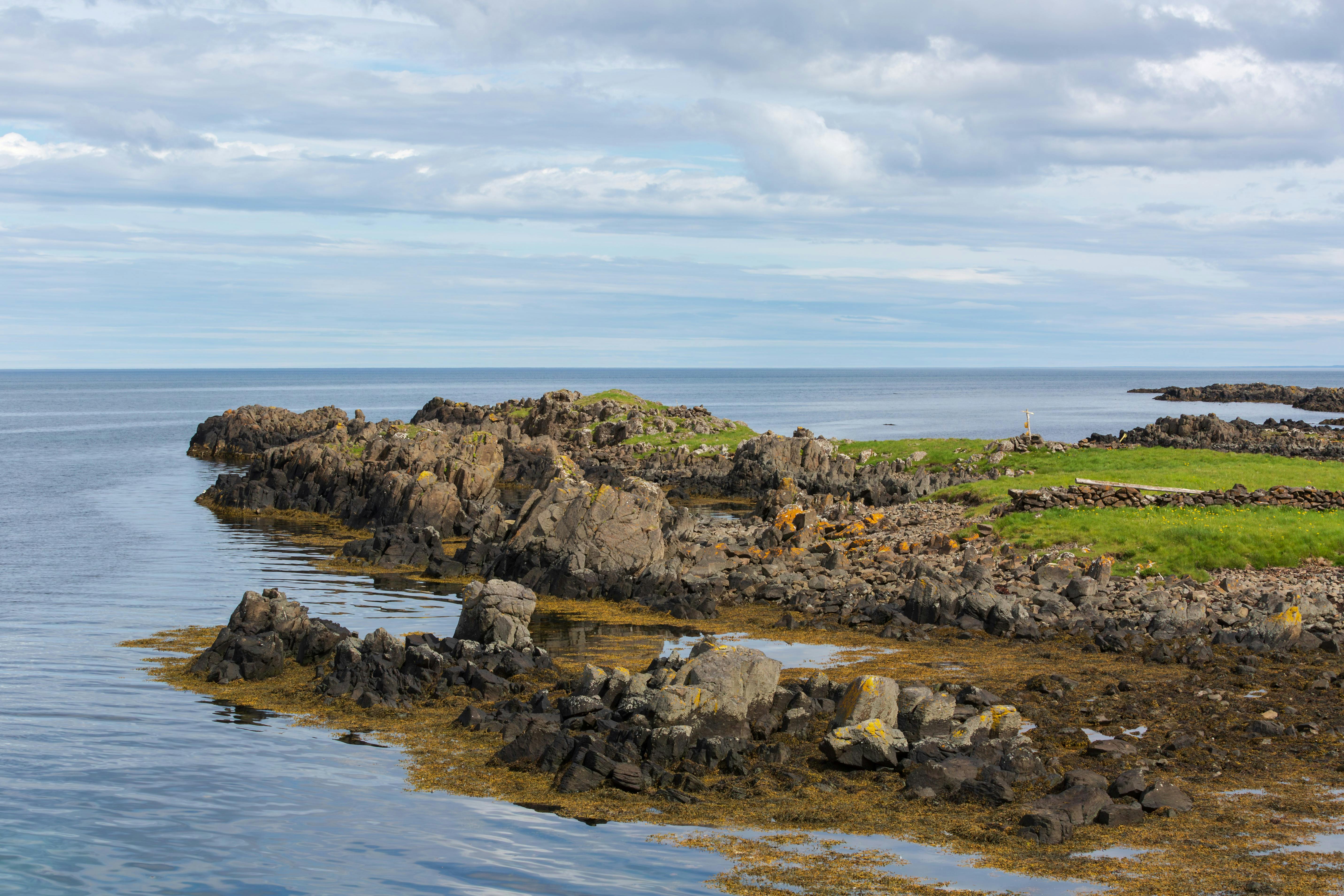 A rocky shoreline with a lighthouse in the distance