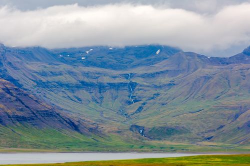 Free Breathtaking view of Iceland's rugged mountains with cloud coverage and lush greenery. Stock Photo