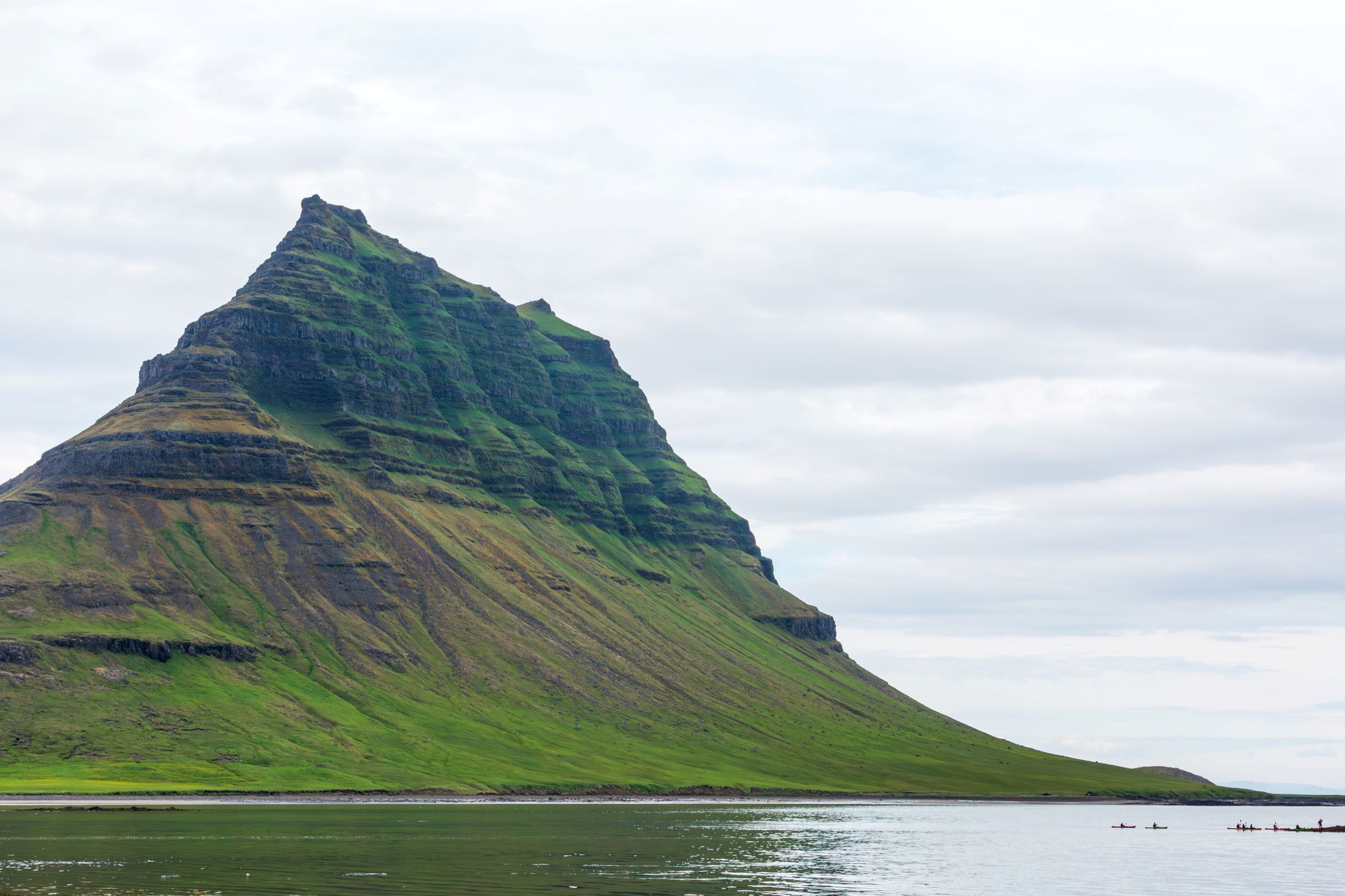 Capture of Kirkjufell mountain by the coast in Iceland, showcasing unique geological features.