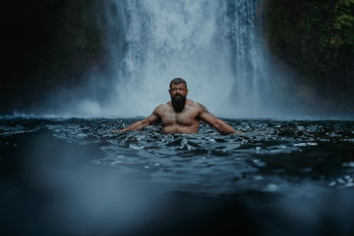 Bearded Man in River against Waterfall