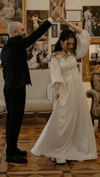 A couple elegantly dancing in a classic wedding setting surrounded by artwork.