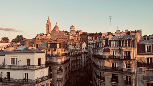 Aerial view of Parisian architecture and the Sacré-Cœur Basilica at sunset, showcasing classic urban beauty.
