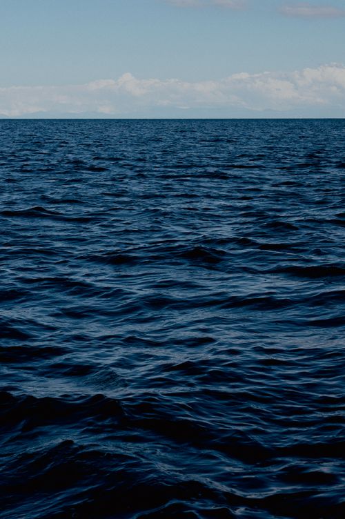 Free Wide view of calm ocean waves with a clear azure sky, perfect for tranquil themes. Stock Photo