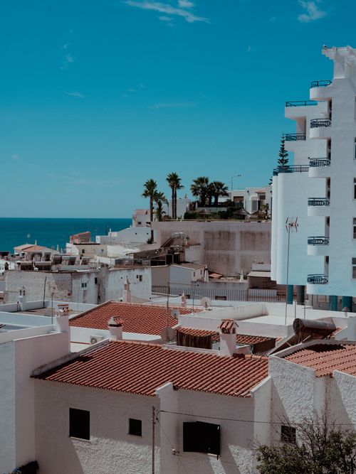 Free A picturesque view of a coastal village with Mediterranean architecture under a clear blue sky. Stock Photo