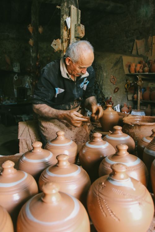 Free An elderly artisan skillfully molds clay into beautiful pottery in an indoor workshop setting. Stock Photo