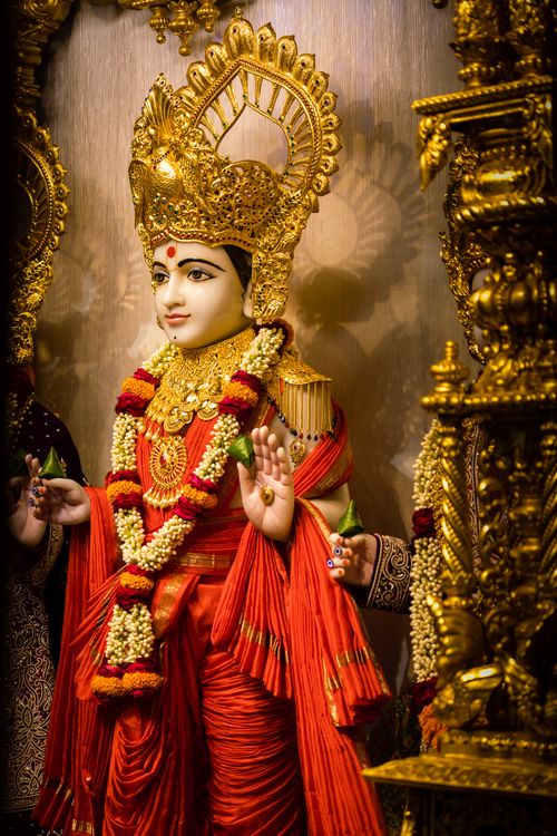 Free Intricate golden statue of a Hindu deity adorned with garlands inside a temple. Stock Photo