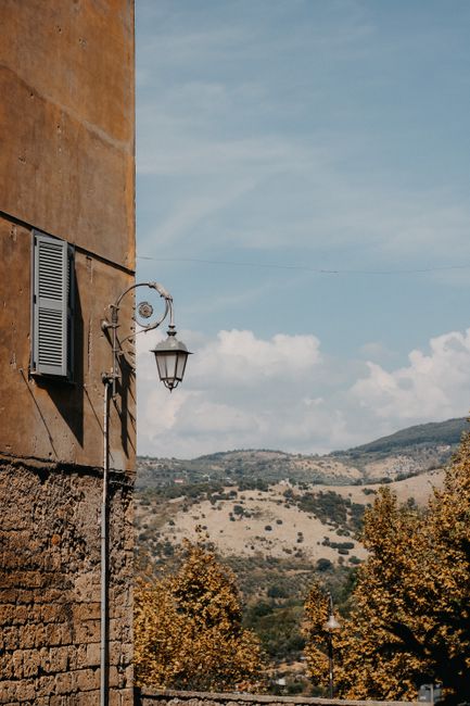 Charming vintage setting with a wall lantern and hills under a clear sky.
