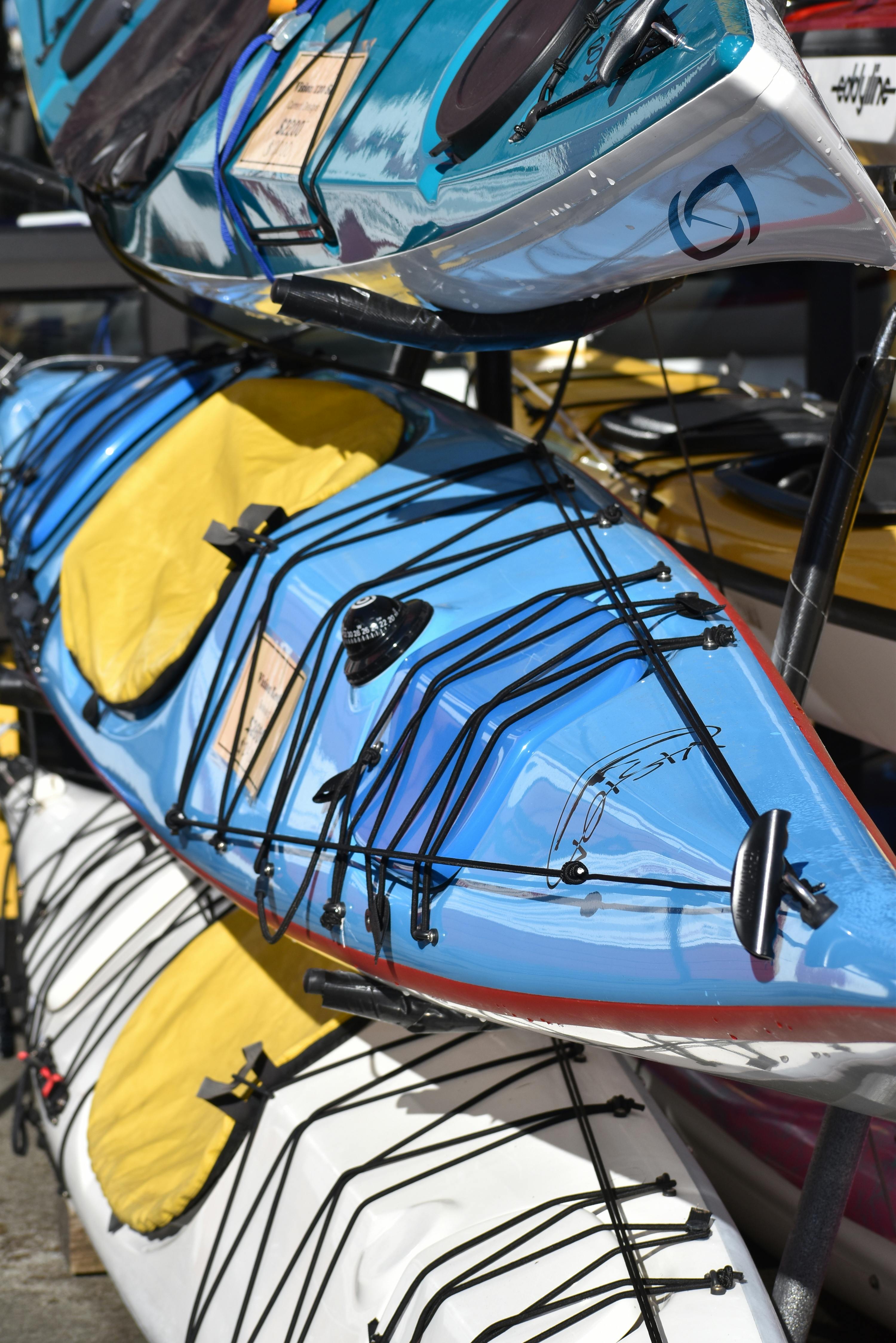 Colorful stack of kayaks stored outdoors, ideal for adventurous water activities.