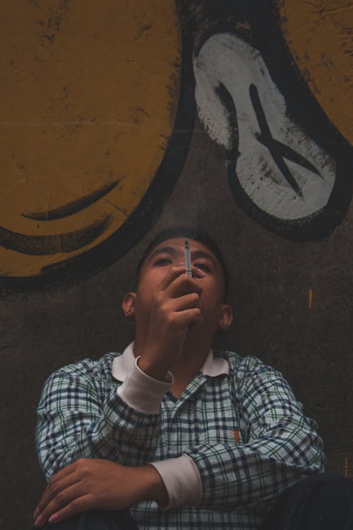 Free Man Smoking Near Graffiti Filled Wall Stock Photo