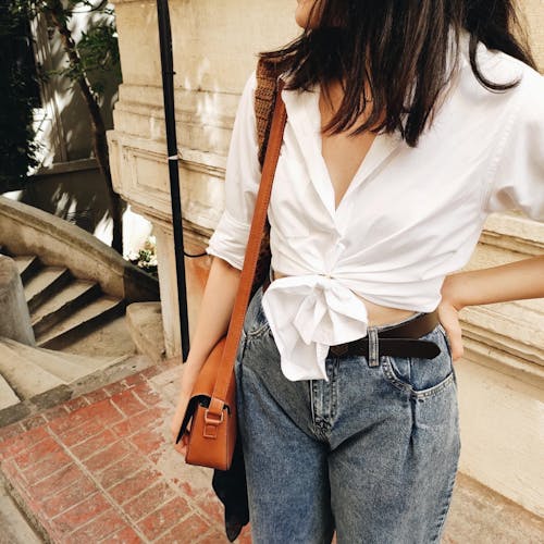 Woman in Jeans and White Shirt Standing beside a Building 