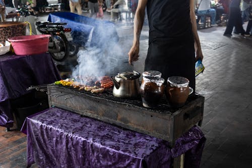 A Man Grilling Sausages on a Grill on a Street 