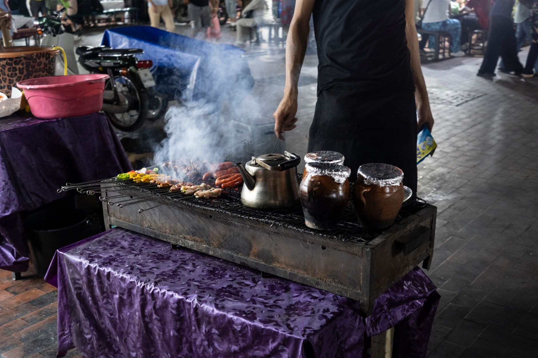 Skewers of seekh kebab grilling over coals in the lane behind Jama Masjid