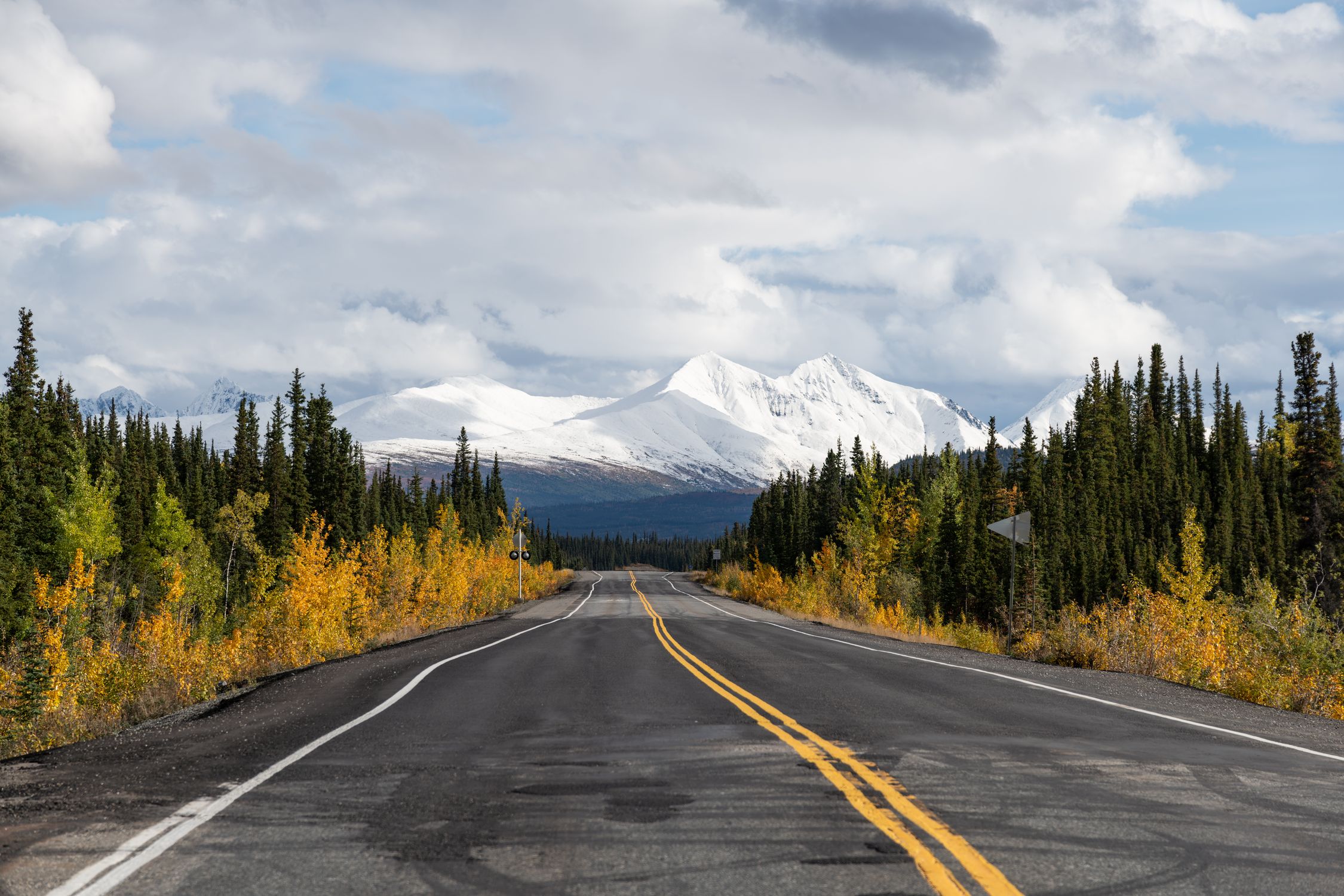 A picturesque road leading to snowcapped mountains in Alaska during fall.