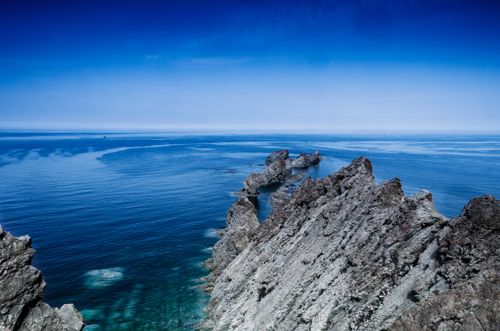 Free Captivating aerial shot of rugged coastline and serene blue sea. Stock Photo