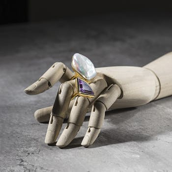 Stylish pearl and amethyst rings displayed on a wooden mannequin hand, perfect for a jewelry showcase.