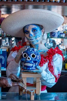 Colorful Catrina with skull makeup and traditional attire in a bar in Ciudad de México.