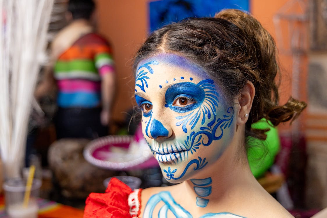 A woman with blue face paint and a skull on her face · Free Stock Photo