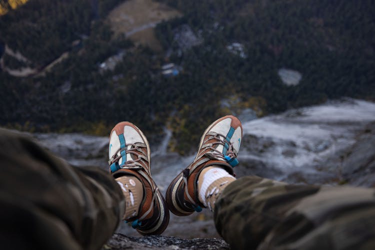 Legs And Shoes Of Person Sitting On Rocks