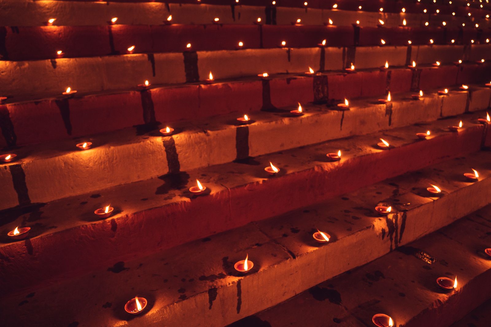 Rows of small oil lamps burning along wide stone steps on a festival evening