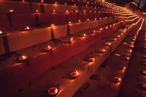 Free Illuminated clay lamps arranged in rows on steps during a night festival. Stock Photo
